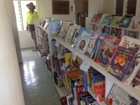 Children's books on shelves, man in hat standing in the distance